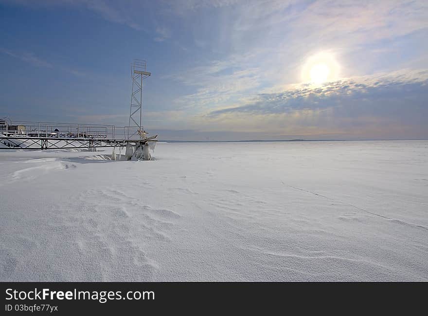 View of frozen sea, pier under snow and sunset, Russia. View of frozen sea, pier under snow and sunset, Russia.