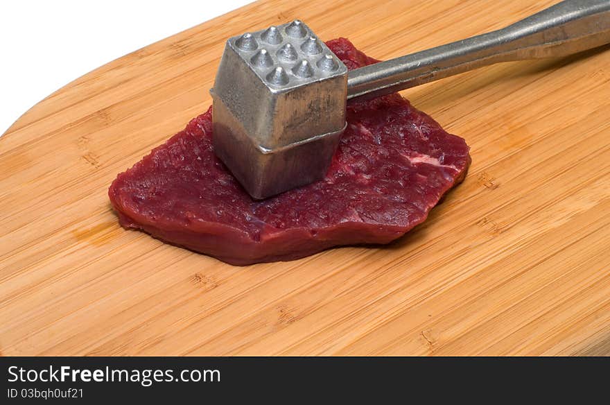 Piece of beef and a kitchen mallet on a wooden cutting board. Piece of beef and a kitchen mallet on a wooden cutting board.