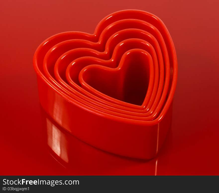 A closeup of red plastic cookie cutters on a red plastic surface