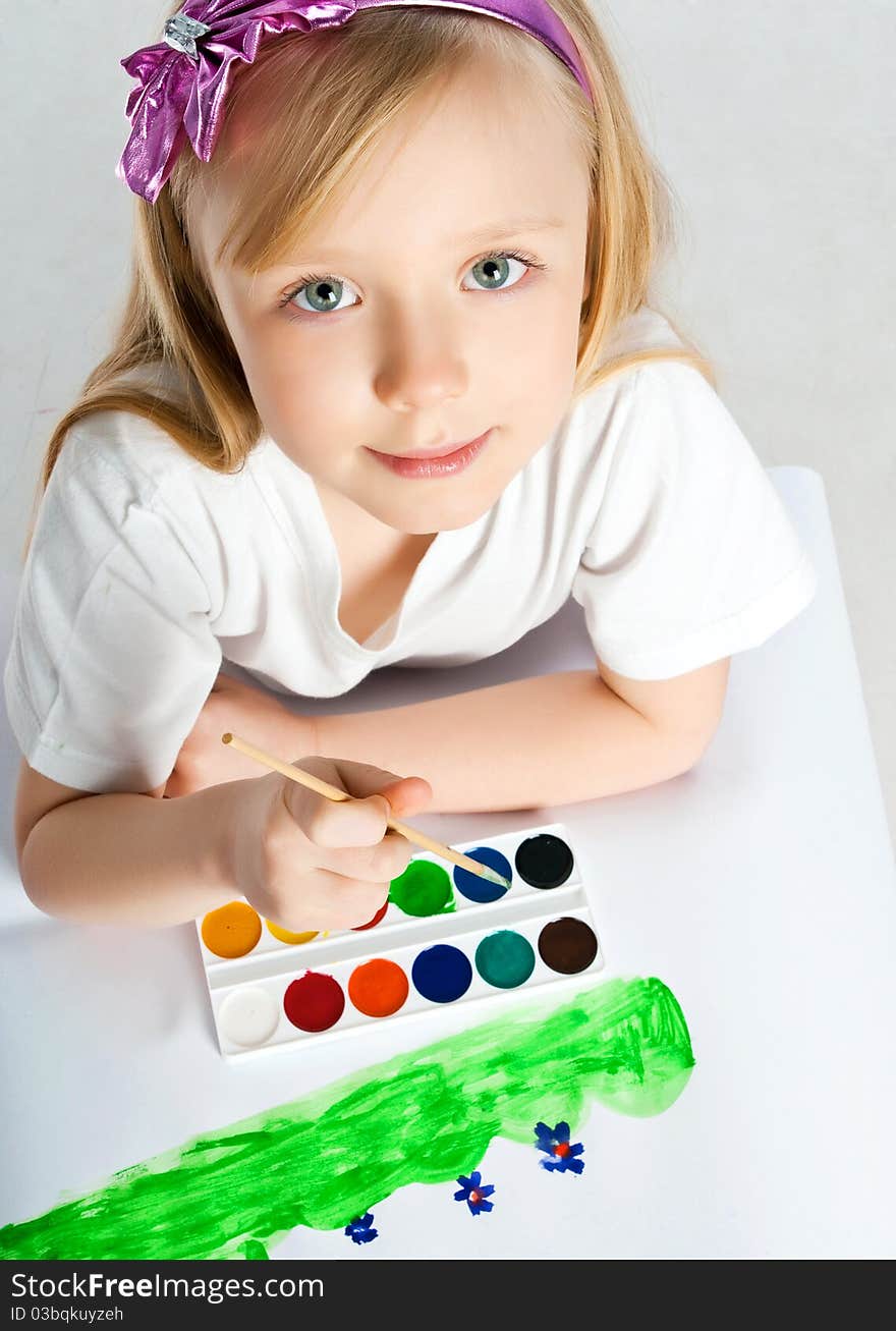 Cute little girl with a brush and paints