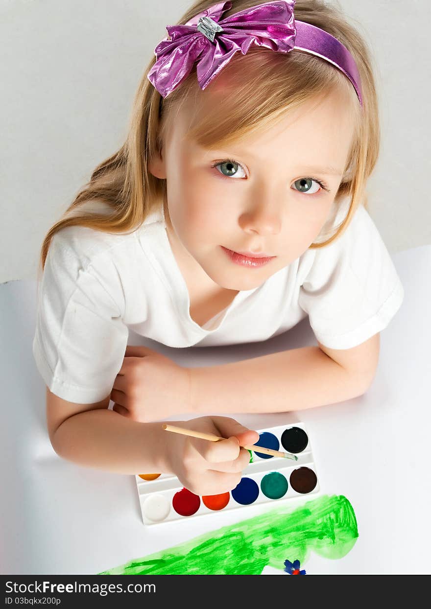 Cute little girl with a brush and paints