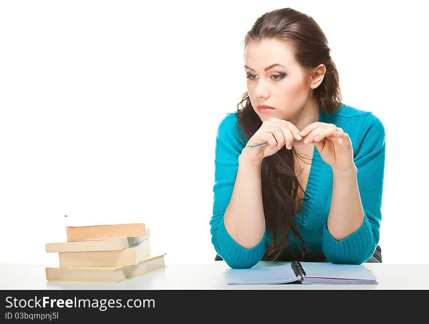 Thoughtful girl with a book sitting at a table on a white background. Thoughtful girl with a book sitting at a table on a white background