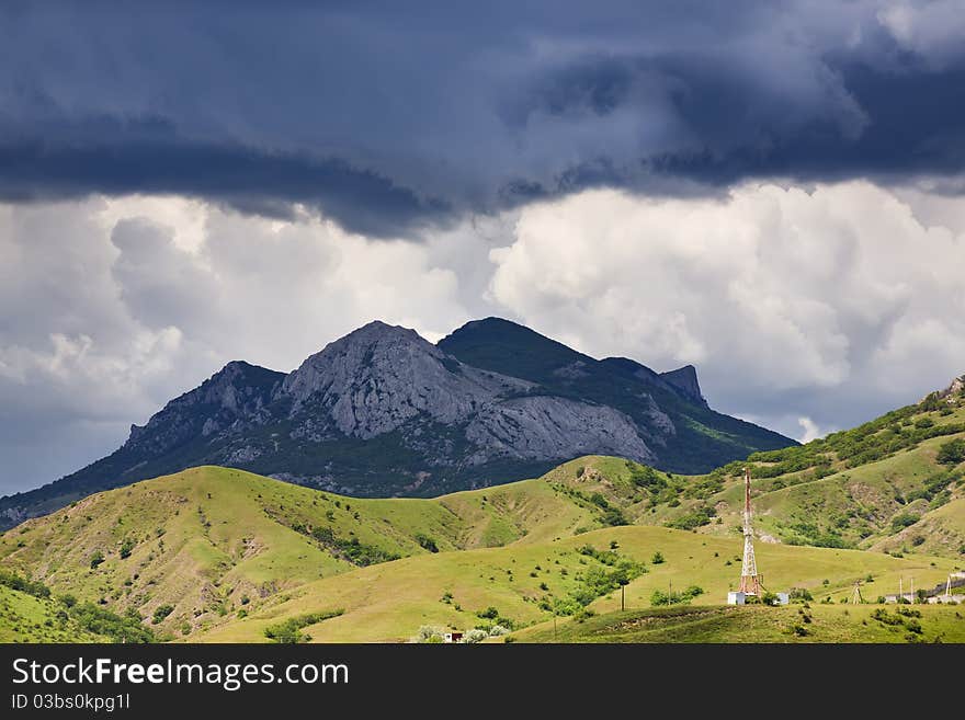 Drama clouds above mountains and a valley with telecommunication tower