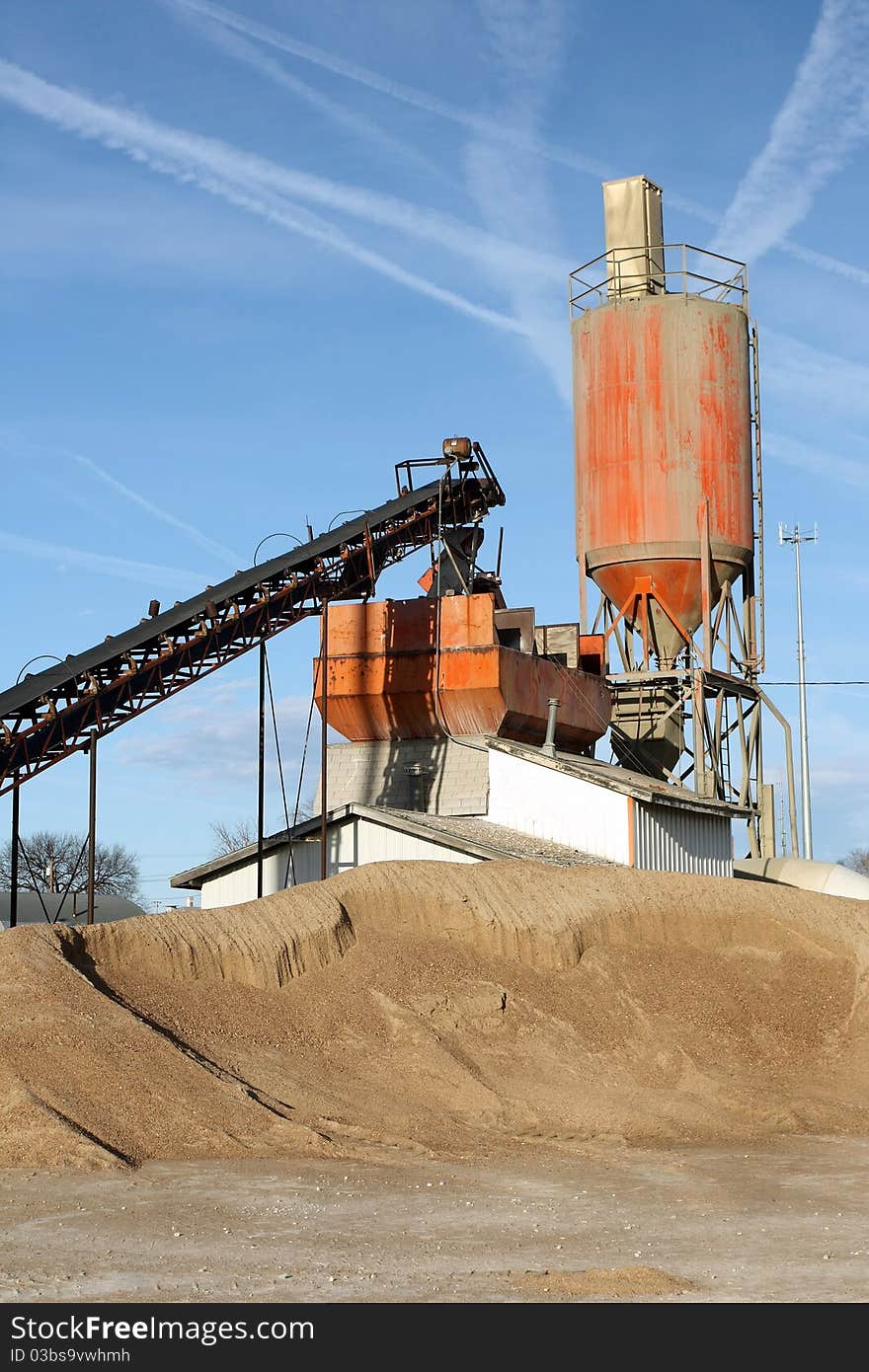 Vertical view of small town cement plant on clear blue day. Vertical view of small town cement plant on clear blue day