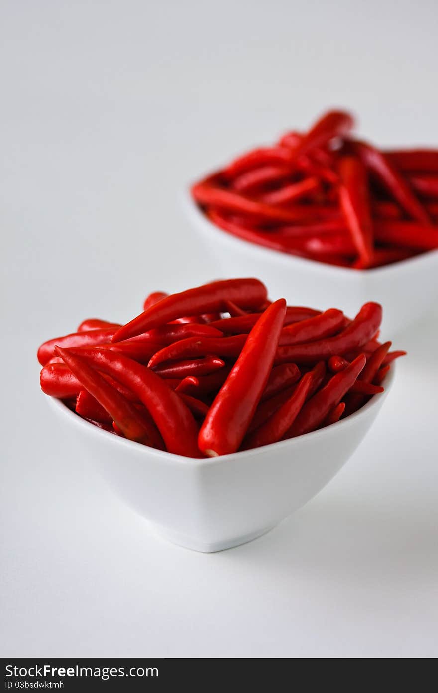 Red hot chili peppers in white cups on white background