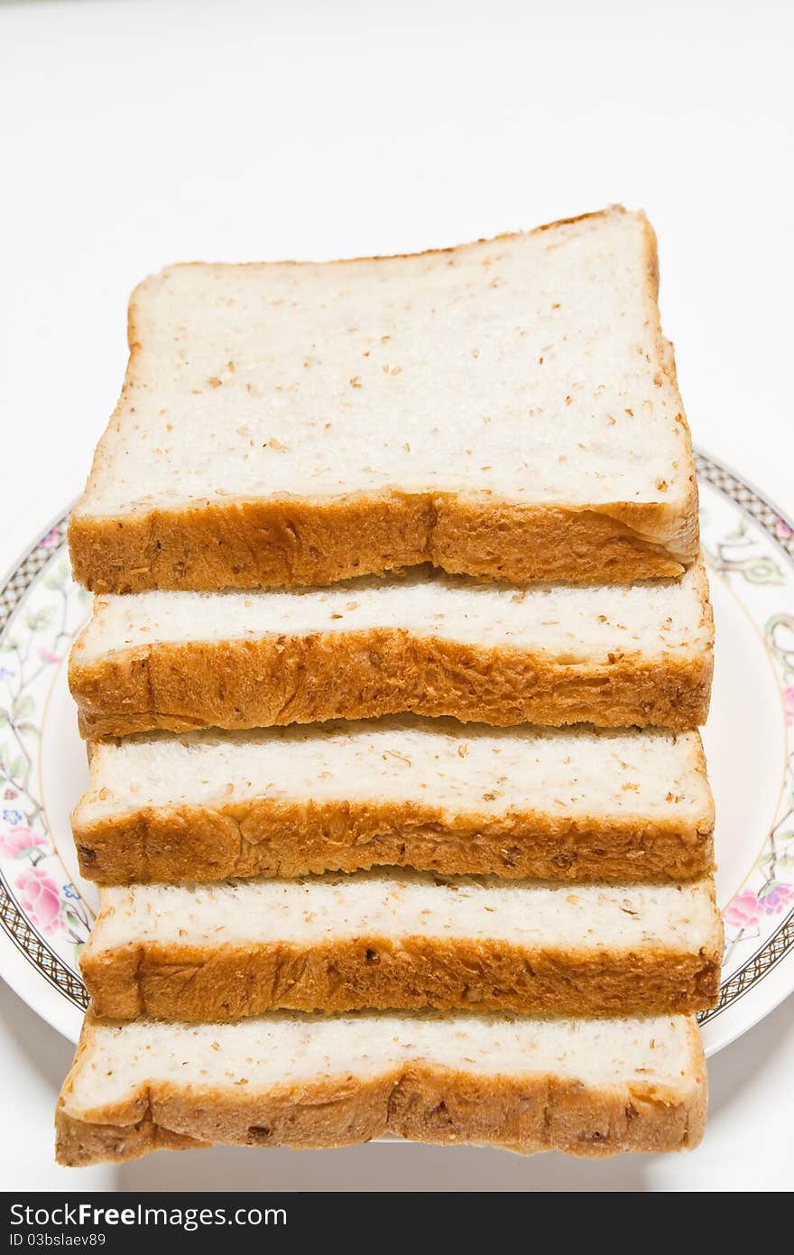 Sliced of whole wheat bread in a plate on white background