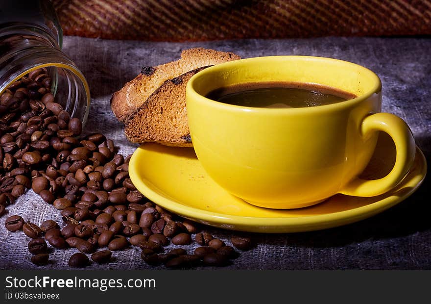 Black coffee, a yellow cup and coffee beans.