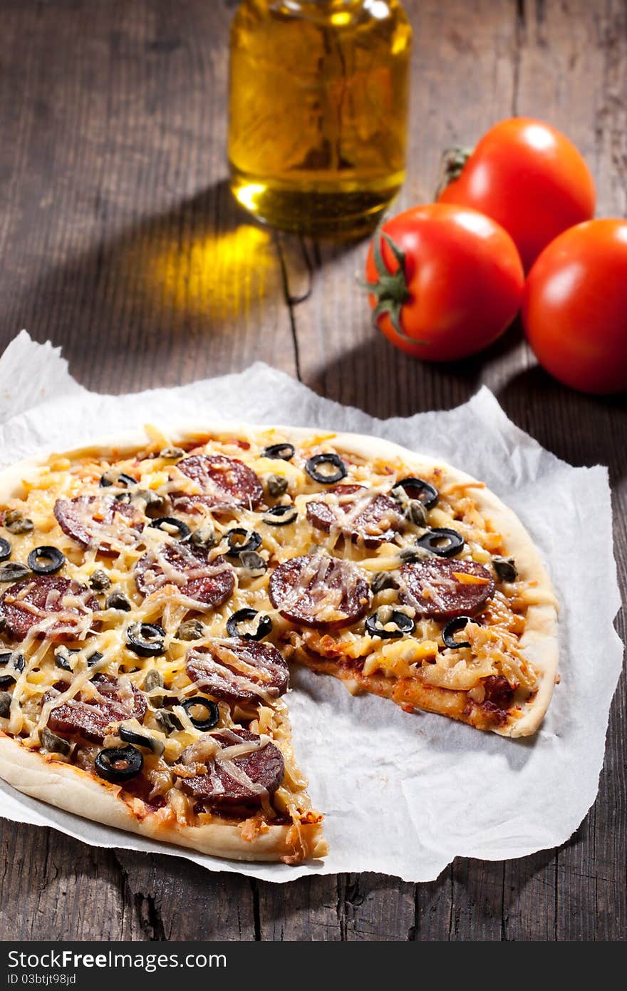 Homemade pizza with salami, cheese and black olives.