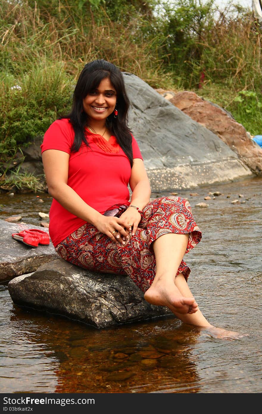 Indian Woman In Red Dress Sitting On A Rock