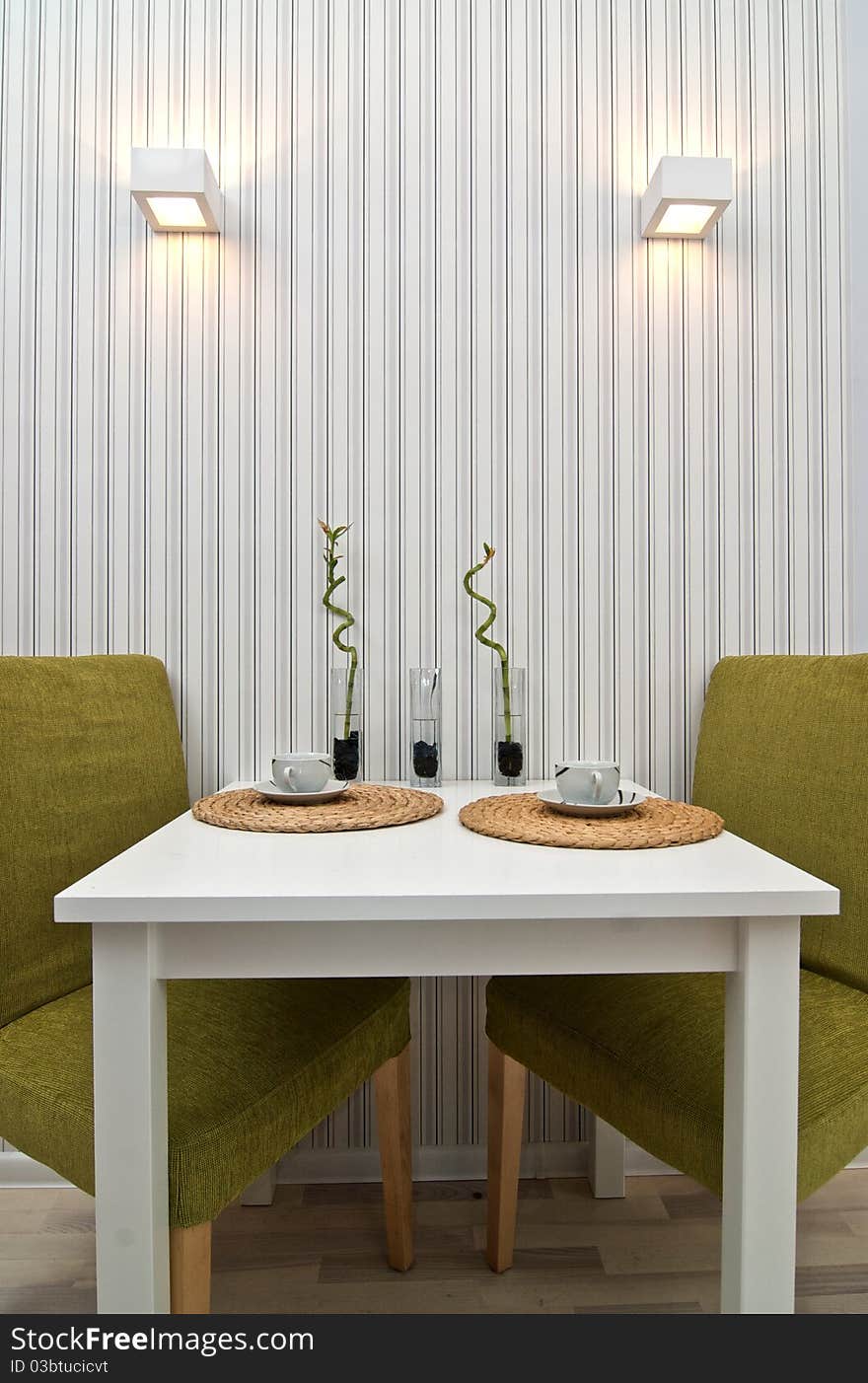 Table with two chairs near the wall, with two cups on it