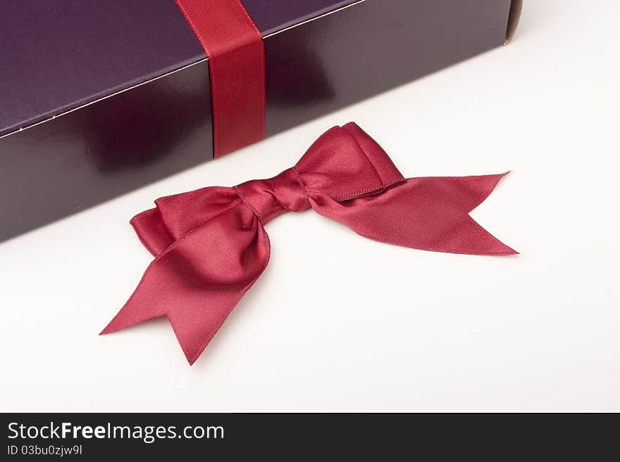 Gift box of darkly violet colour with a ribbon on a white background.