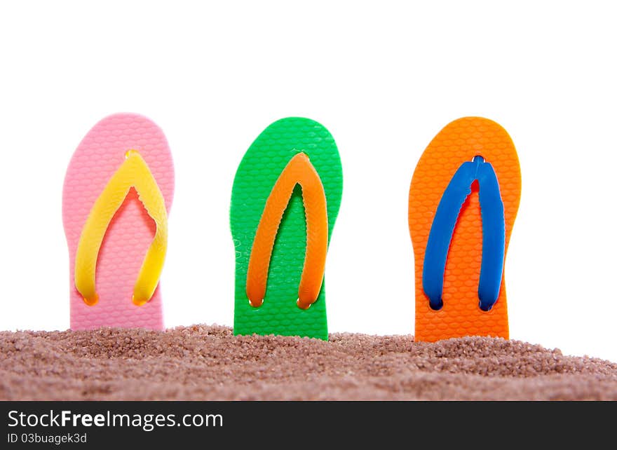 Modern colorful summer thongs in beach sand against a white isolated backgroiund. Modern colorful summer thongs in beach sand against a white isolated backgroiund