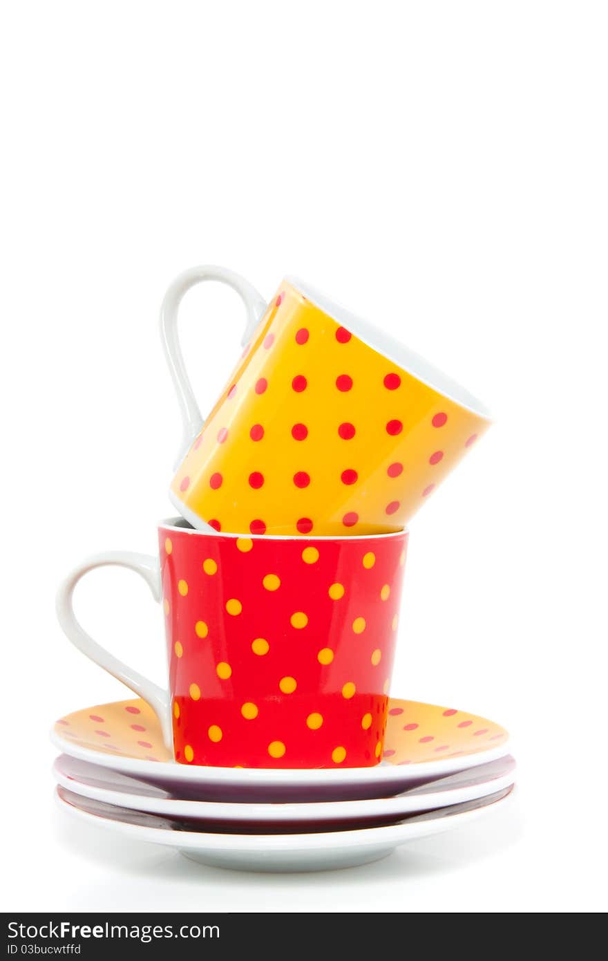 Colorful red and orange dotted cups and saucers isolated over white