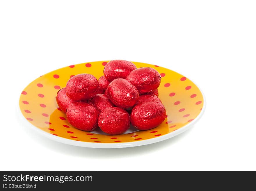 Chocolate easter eggs in red foil on a dotted saucer isolated over white