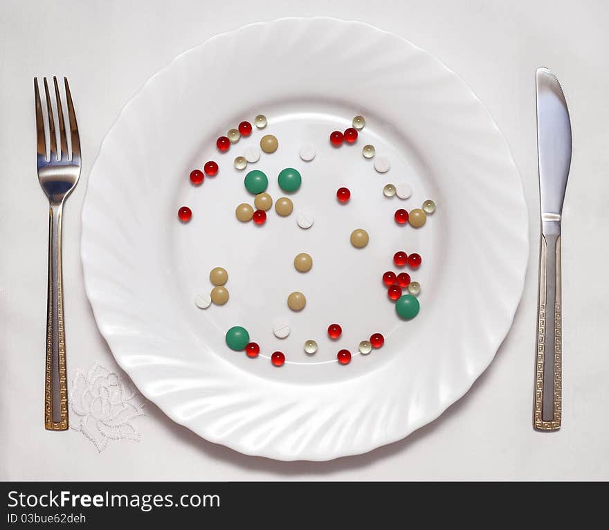 Vitamin photo on a white plate, the fork and a knife nearby lie. Vitamin photo on a white plate, the fork and a knife nearby lie