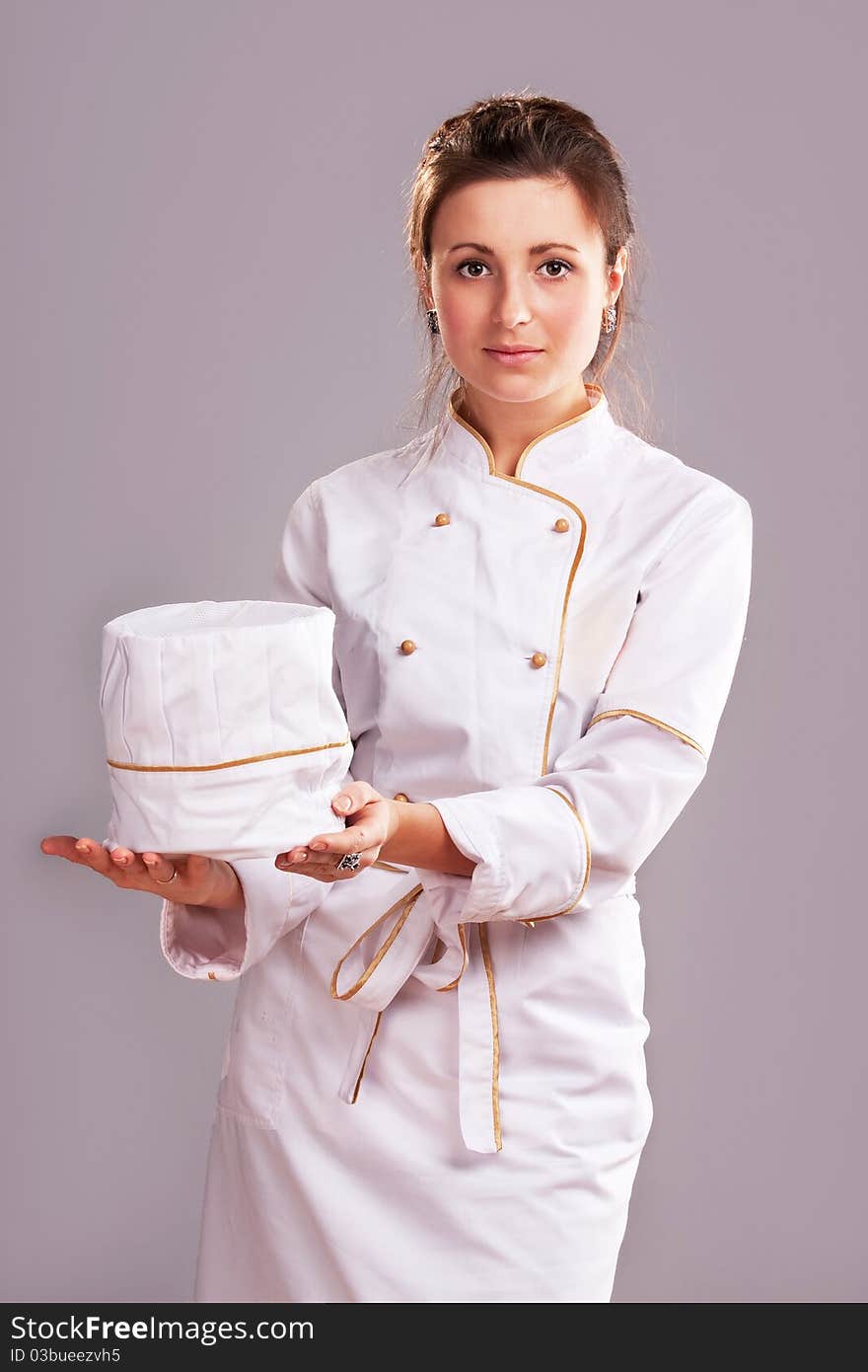 Young woman in white chef dress with hat. Young woman in white chef dress with hat