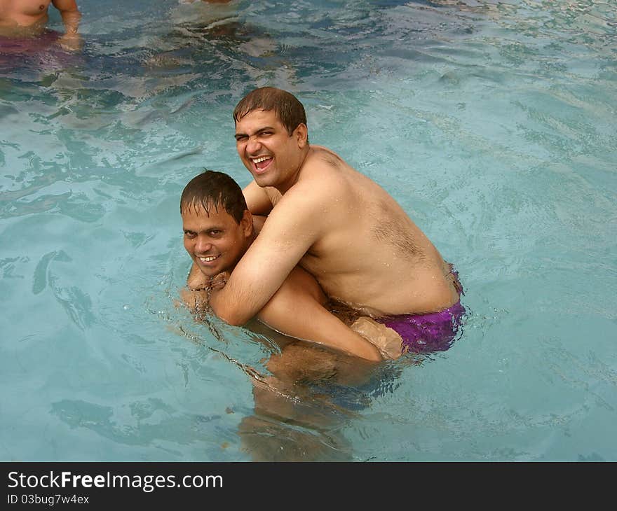 A dark Indian man lifting another in the swimming pool. A dark Indian man lifting another in the swimming pool.