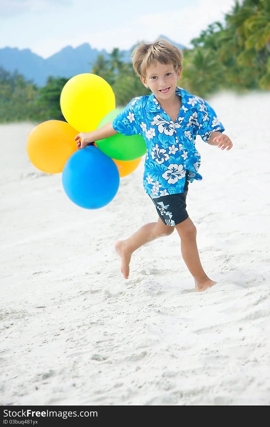 Young happy boy running with balloons on beach