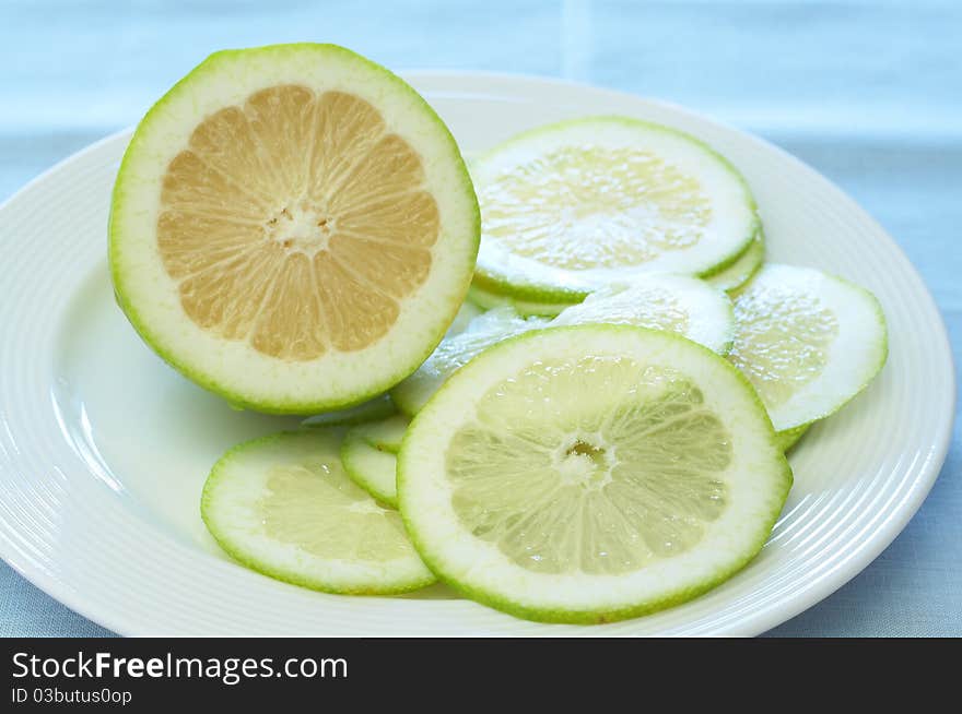 Closeup of lime lemons on a white plate. Focus on the slice. Closeup of lime lemons on a white plate. Focus on the slice.