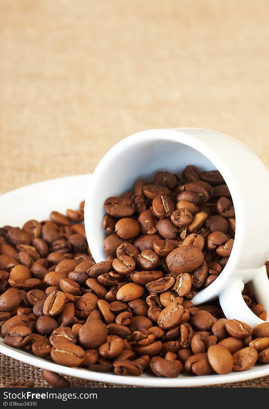 Small espresso cup filled with roasted coffee beans. Small espresso cup filled with roasted coffee beans