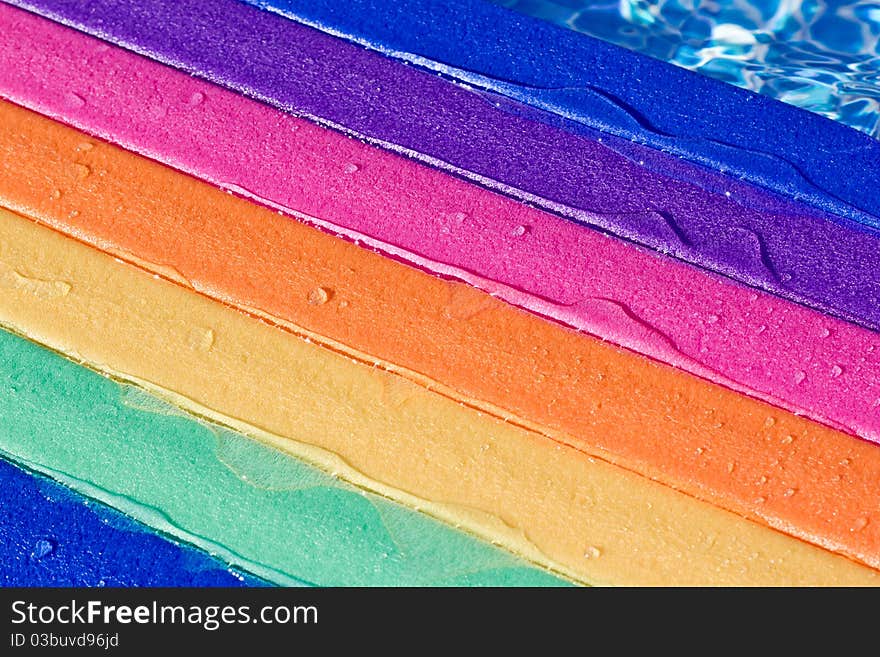 A rainbow colored water board in a pool with water on it. A rainbow colored water board in a pool with water on it