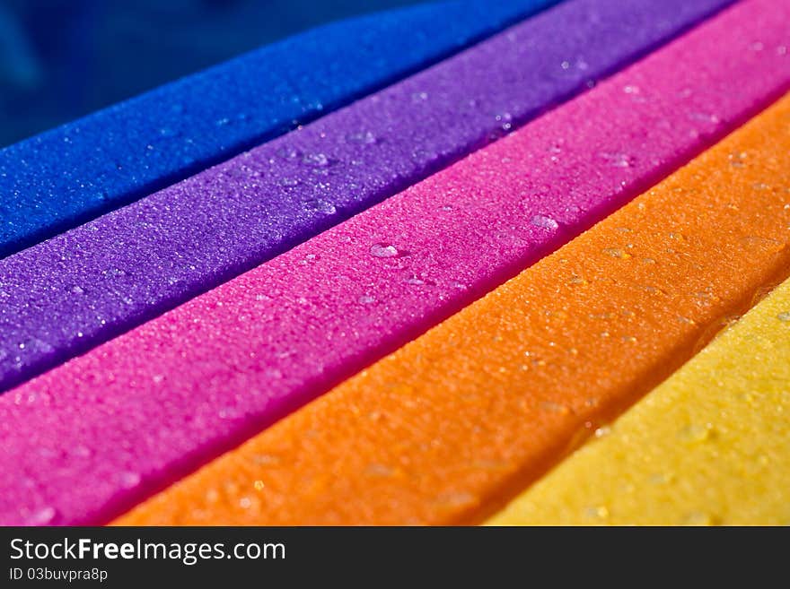 A rainbow colored water board in a pool with water on it. A rainbow colored water board in a pool with water on it