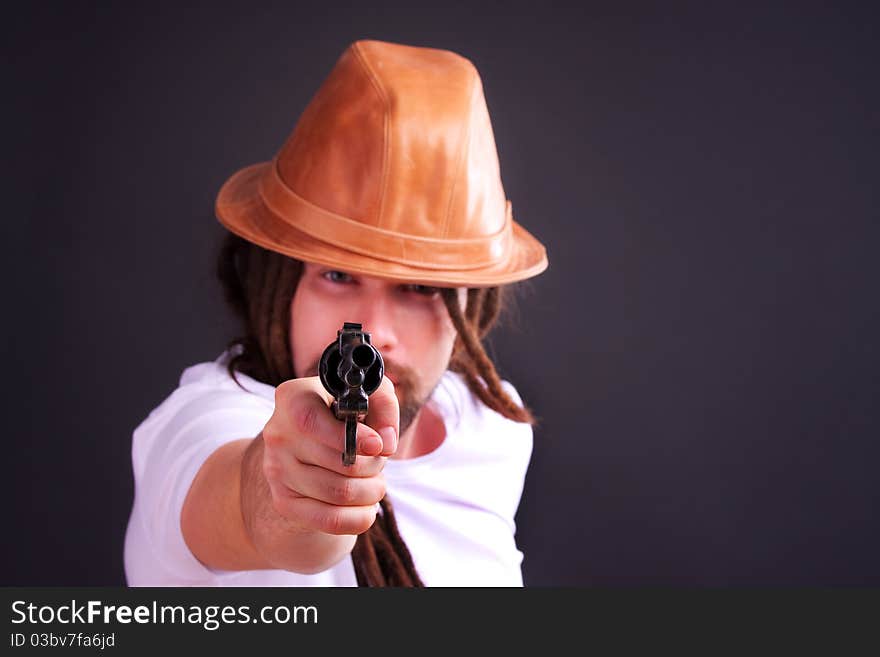 Dour guy wearing a hat holding a gun