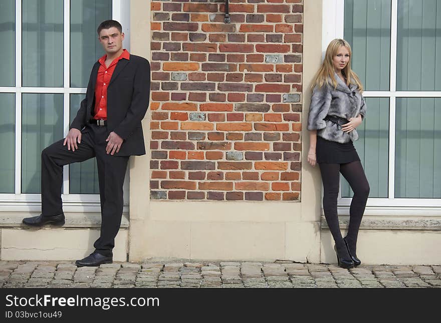 Young couple posing at the brick wall. Young couple posing at the brick wall