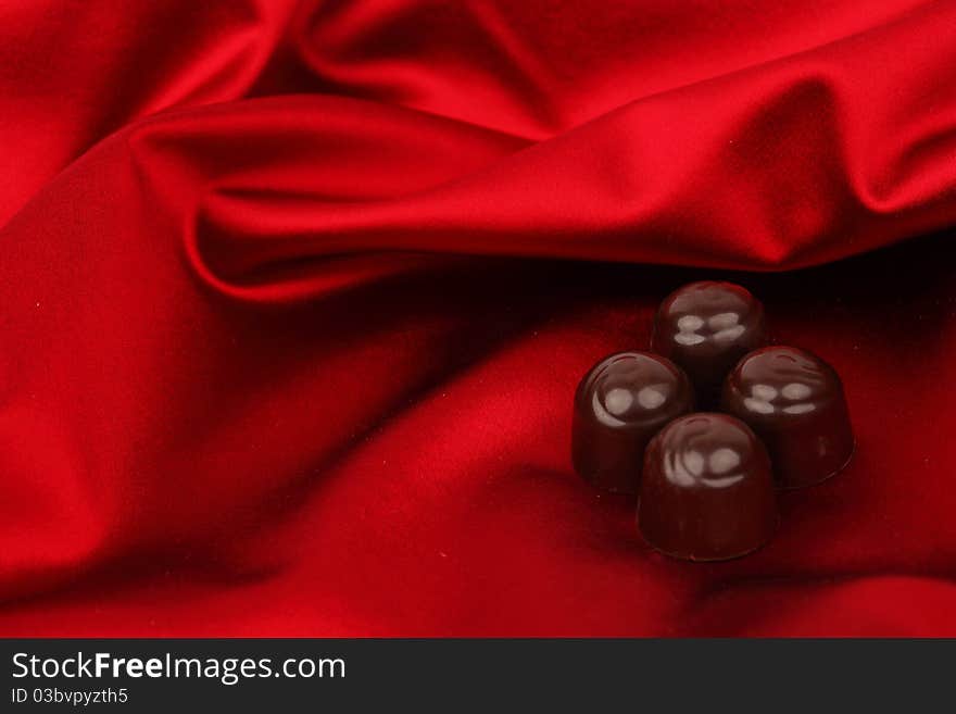 Chocolate candy on red satin background