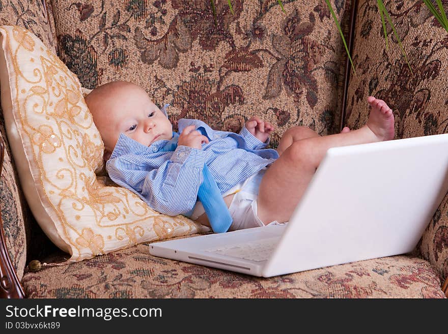 Serious businessman baby sits with the computer on sofa. Serious businessman baby sits with the computer on sofa