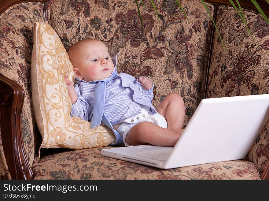 Serious businessman baby sits with the computer on sofa. Serious businessman baby sits with the computer on sofa