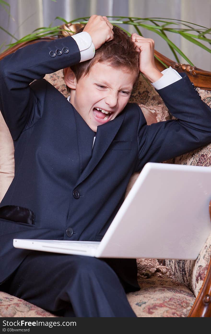 Angry business boy screaming at the computer rend his hair