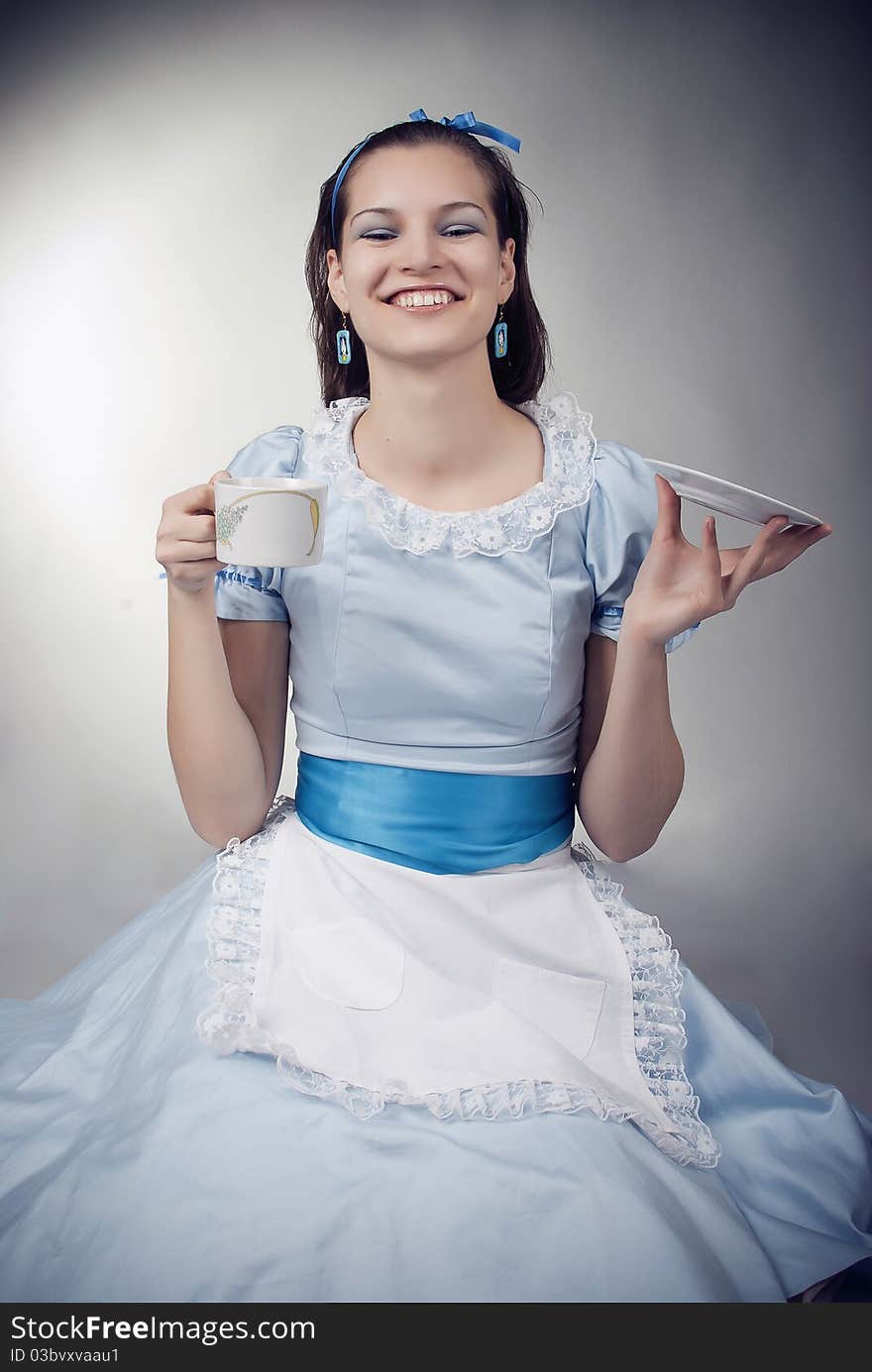 Girl dressed as the character of Alice having tea. Girl dressed as the character of Alice having tea