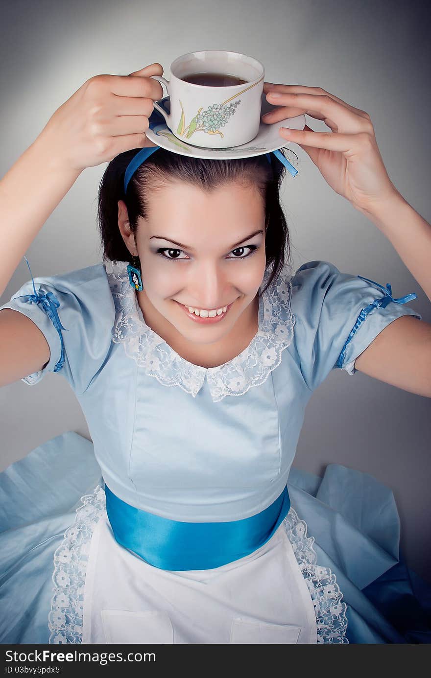 Girl dressed as the character of Alice having tea. Girl dressed as the character of Alice having tea