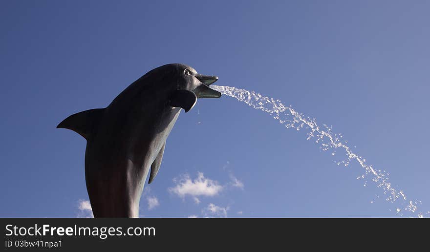 Dolphin fountain spitting on a blue sky