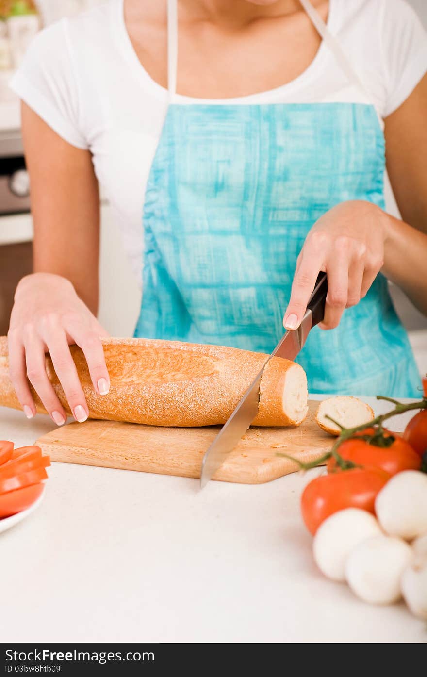 Young woman cutting bread on the kitchen