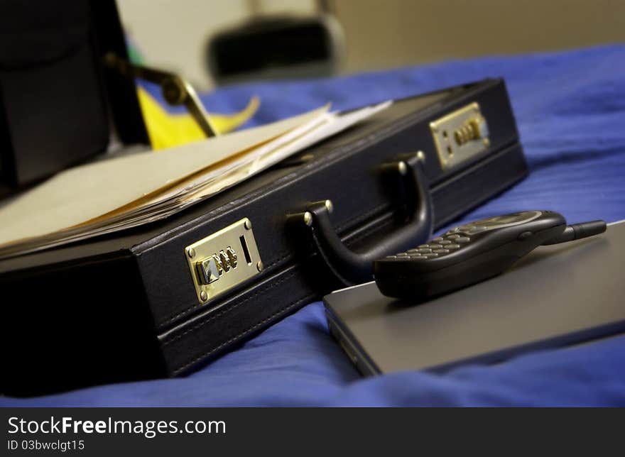 Open briefcase with laptop, phone and papers