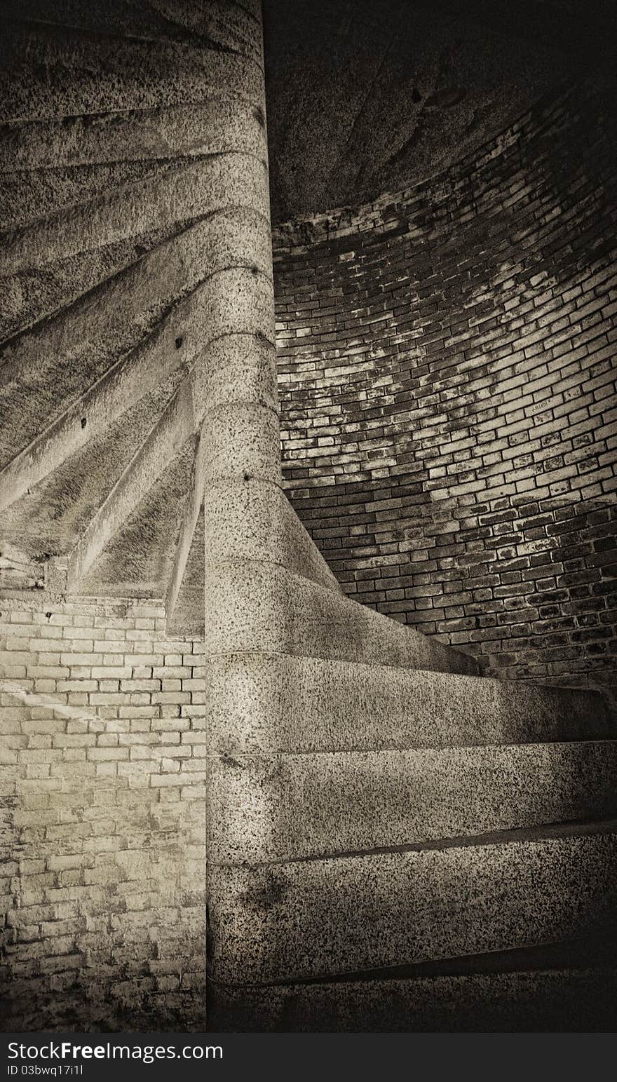 Grim and spooky stone staircase in old brick building. Monochrome sepia. Grain added for atmosphere. Grim and spooky stone staircase in old brick building. Monochrome sepia. Grain added for atmosphere.