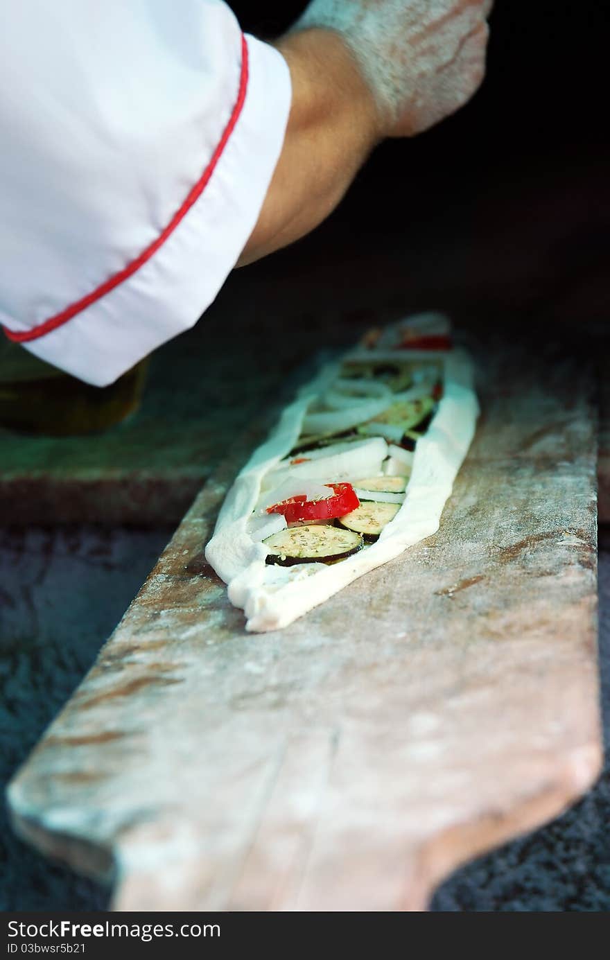 Cook is preparing special Turkish Vegetarian Pide with eggplant,onions and fresh herbs. Cook is preparing special Turkish Vegetarian Pide with eggplant,onions and fresh herbs