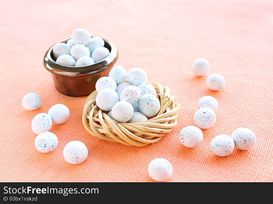 Miniature speckled easter eggs in two containers on an organce cloth