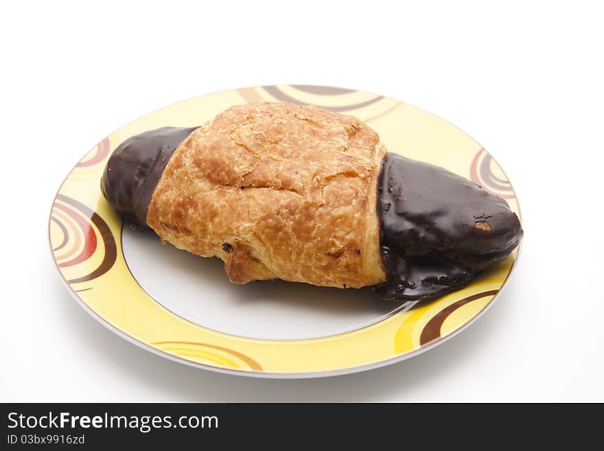 Croissant with chocolates glaze on ceramics plate