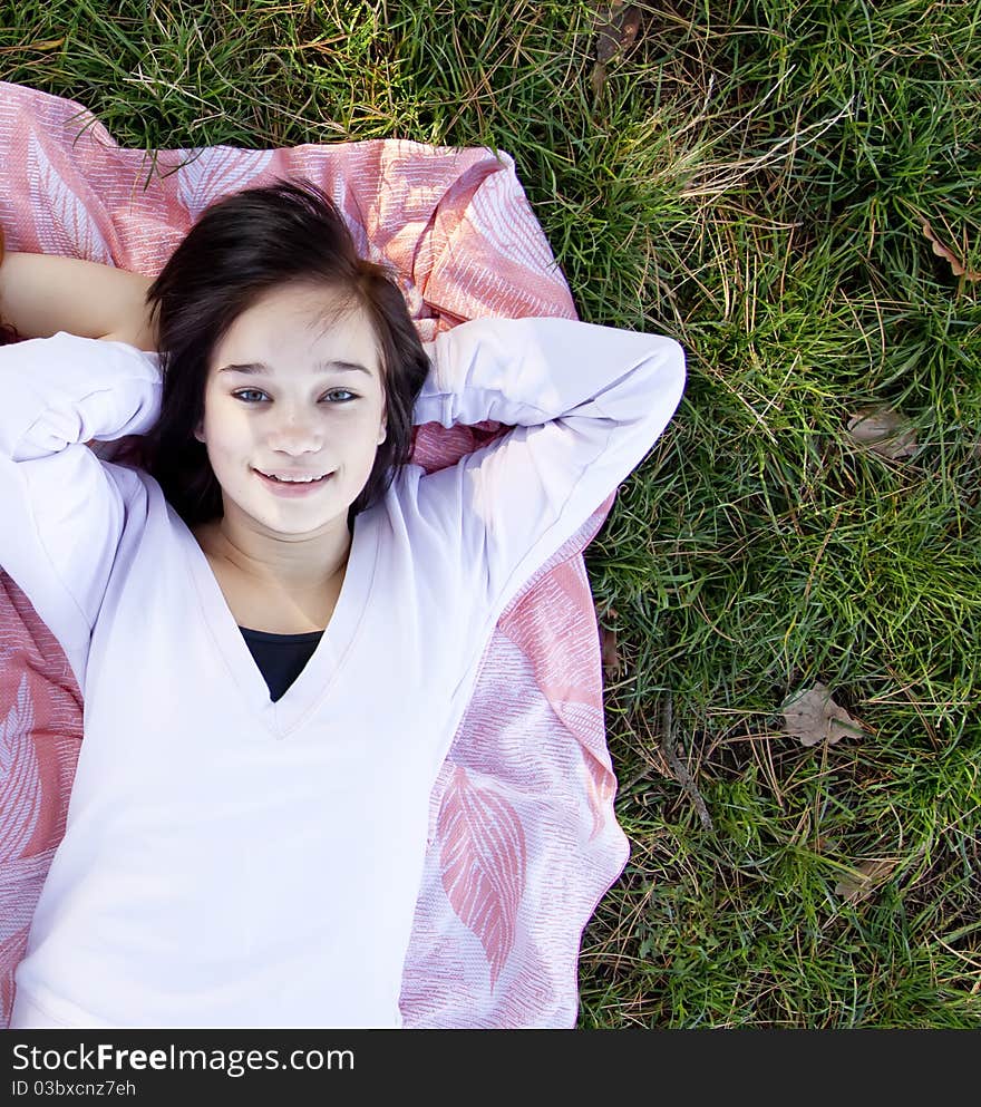 Young teen girl lie at grass.