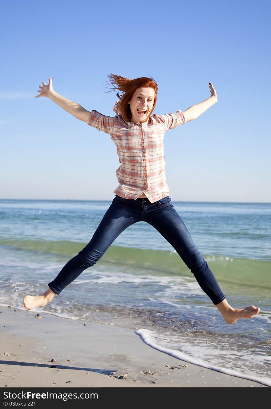 Young beautiful girl jumping at the beach.