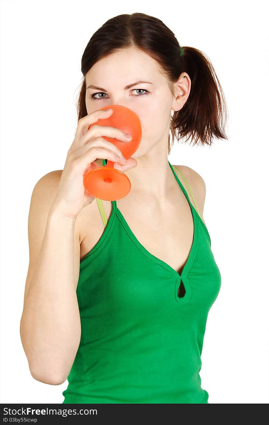 Young girl in green shirt drinking from orange glass, isolated