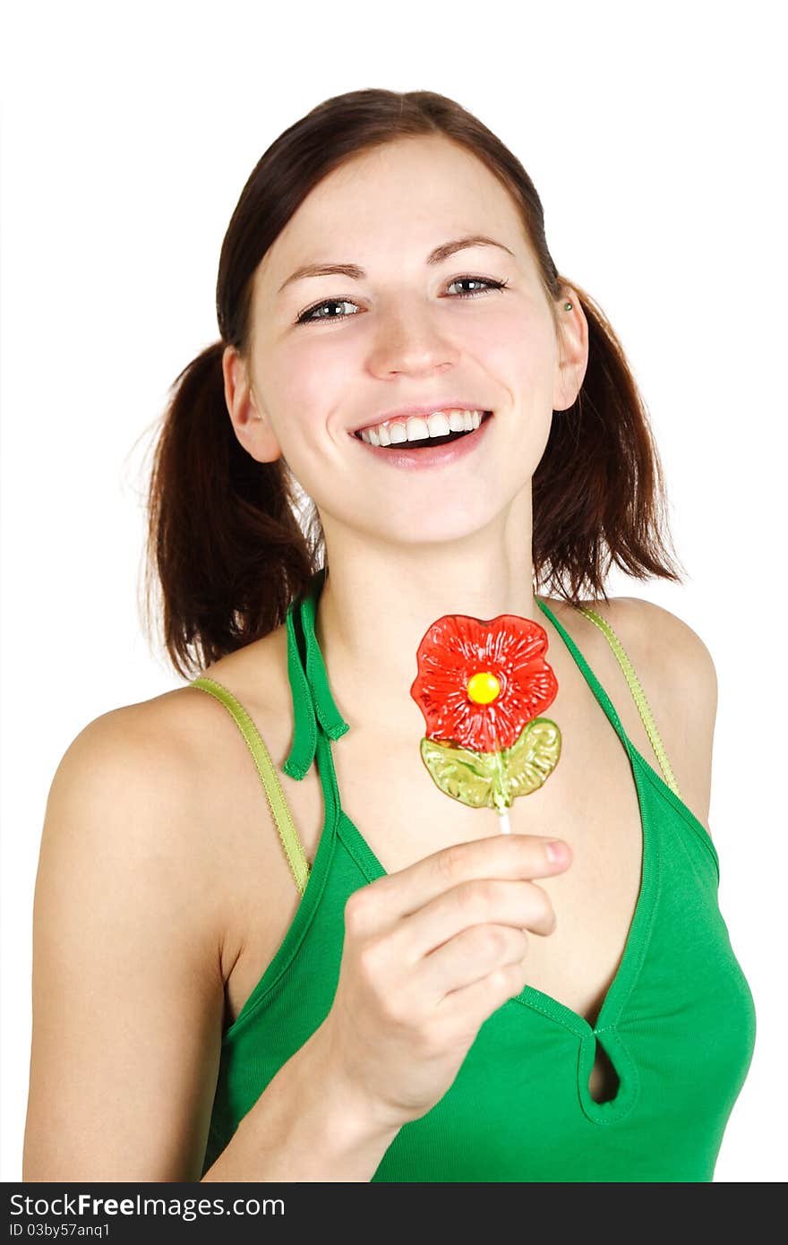 Young girl in green shirt holding flower lollipop and smiling, isolated