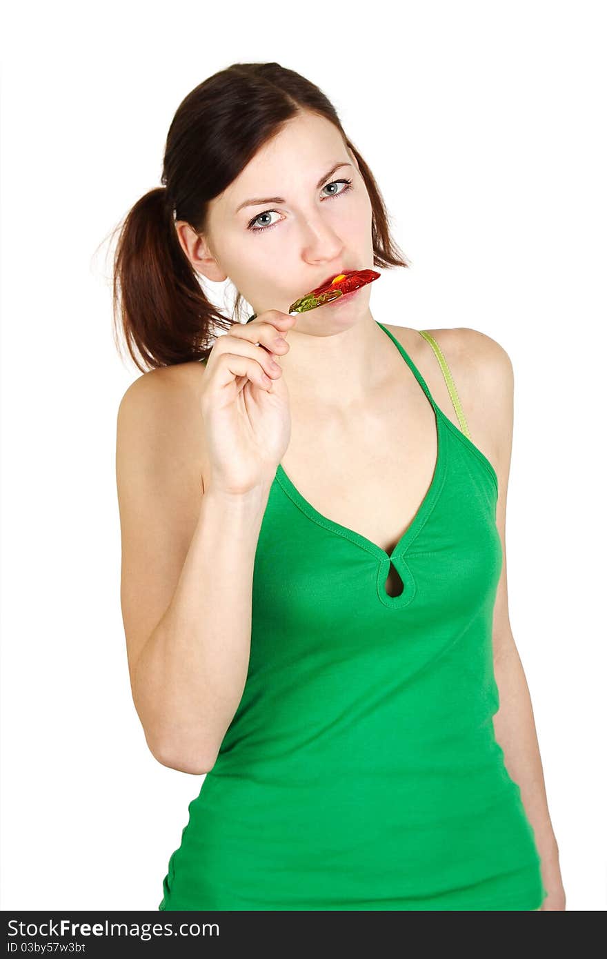 Young girl in green shirt eating flower lollipop and looking at camera, isolated