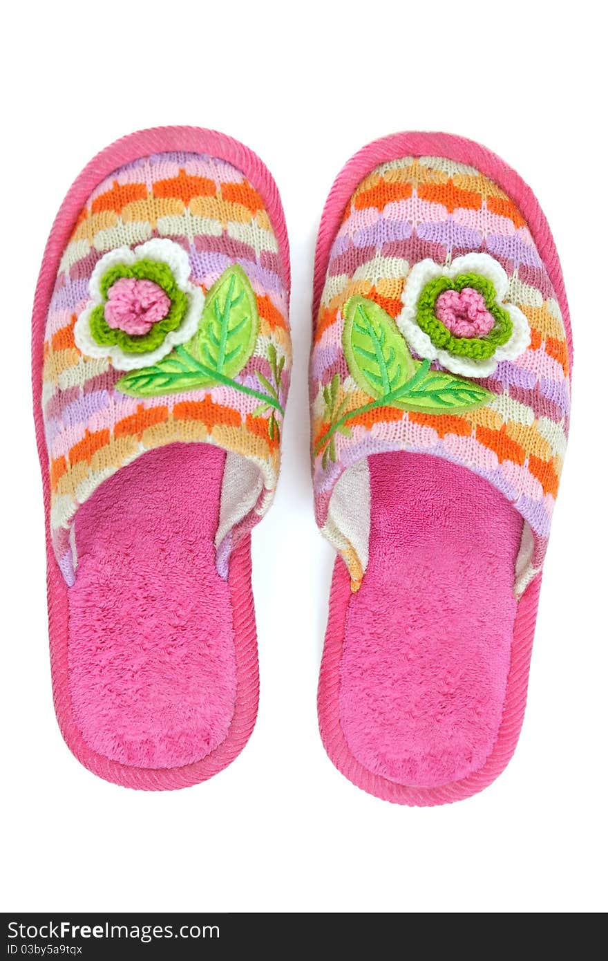 Pair of pink female house slippers with knitted decorative flowers, isolated