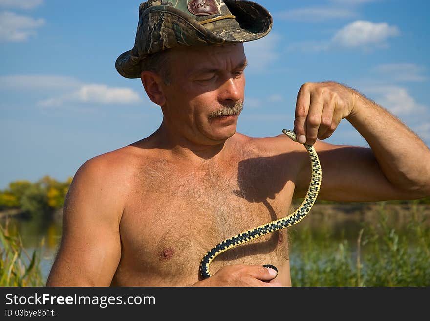 Tanned man caught a a viper and holds it behind his head. Tanned man caught a a viper and holds it behind his head