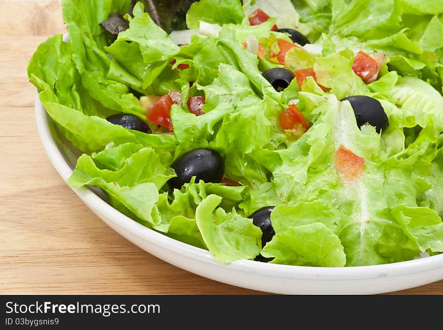 Vegetables salad in plate on wood background