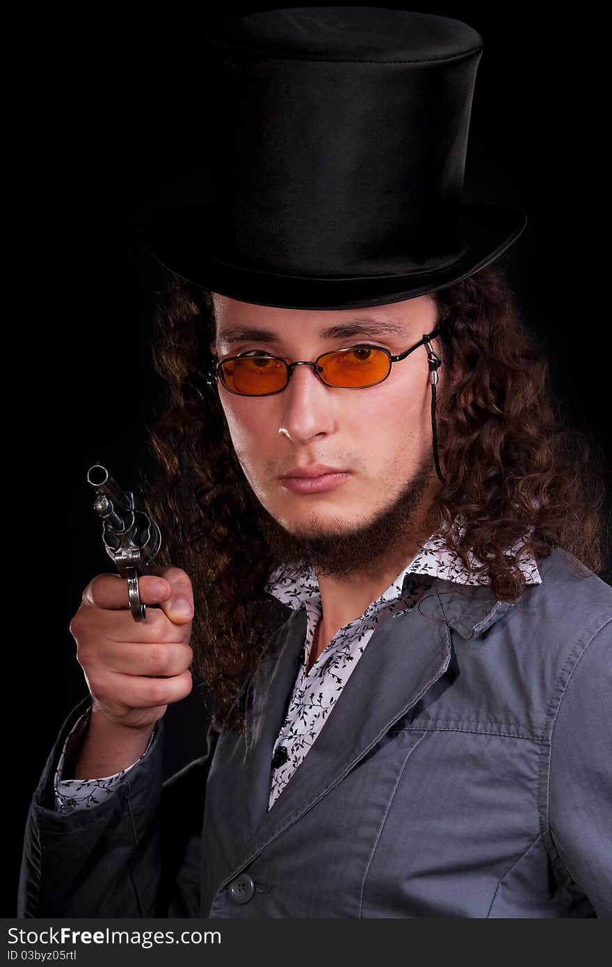 Portrait of the serious man in a top-hat with a pistol in hands